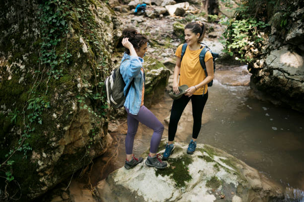 istock Two women taking break while hiking on forest trail 1659802810