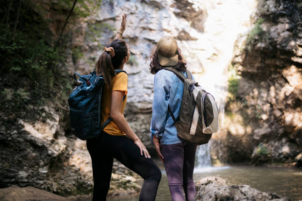 istock Two women hikers looking at beautiful waterfall in forest 1659811949