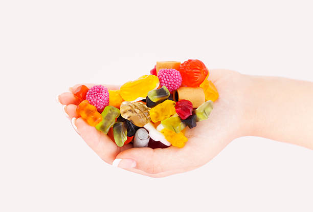 Colorful Sweets mix in woman hand Sweets mix in hands on white candy jellybean variation color image stock pictures, royalty-free photos & images