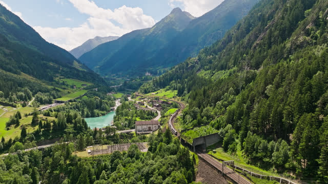 Upward Tilting Drone Shot of Train Passing Hydroelectric Dam Near Gurtnellen, Switzerland