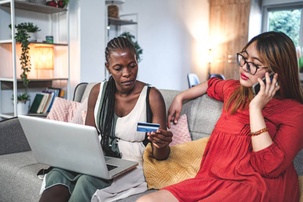 istock Two multiracial female friends having credit card problems while sitting on a couch using laptop 1659858376