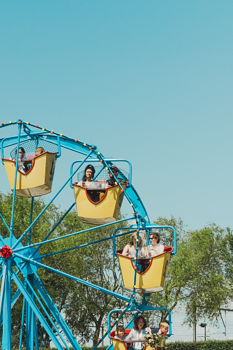 Westerpark, Amsterdam, Netherlands: May 20 2023: Close-up of people enjoying ferris wheel at Rollende Keukens food festival with a strong blue colored theme