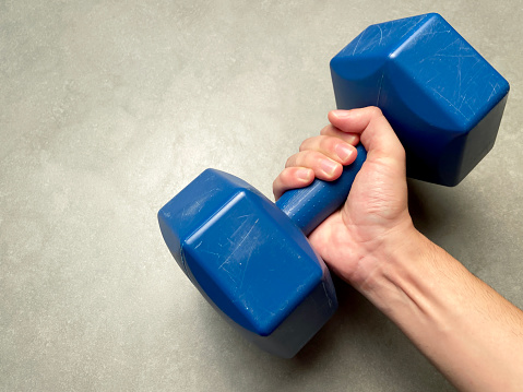 Male hand holding dumbbell weights. Weightlifting training. Fitness training