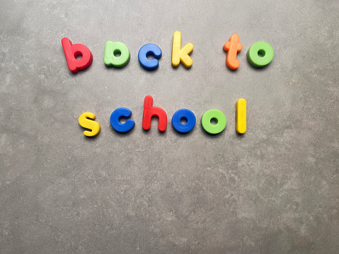 Back to school with multicolored letters on gray background with copy space