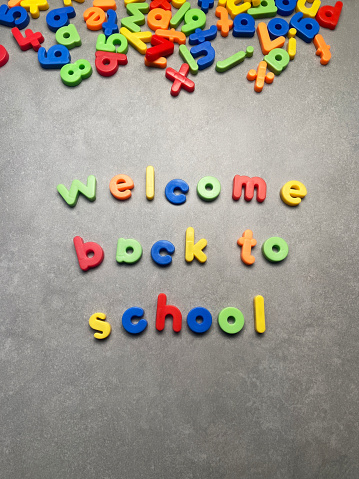 Welcome back to school with multicolored letters on gray background with copy space