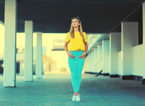 Portrait of stylish caucasian blonde young woman model posing in yellow t-shirt in the city