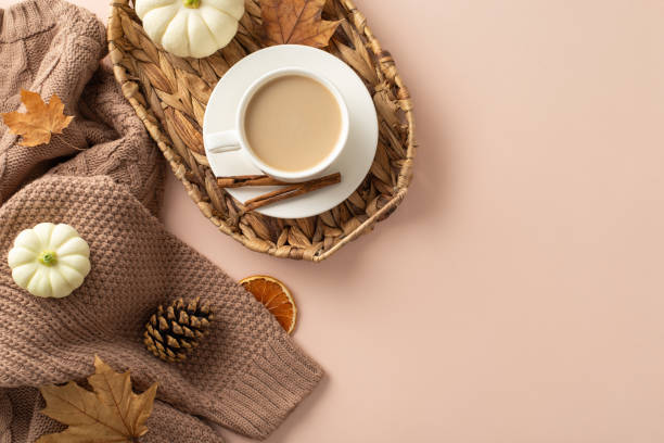istock Autumn comfort visualized. Top view scene with sweater, fresh coffee in wicker garden basket, pattypans, cinnamon, foliage, pine cone, dried orange on pale beige surface, text or ad space included 1659935469