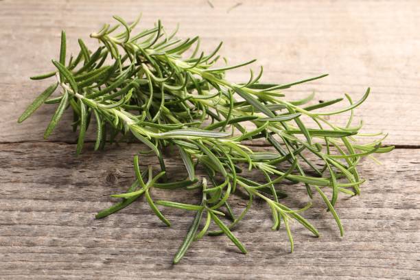 istock Aromatic green rosemary sprigs on wooden table, closeup 1659936623