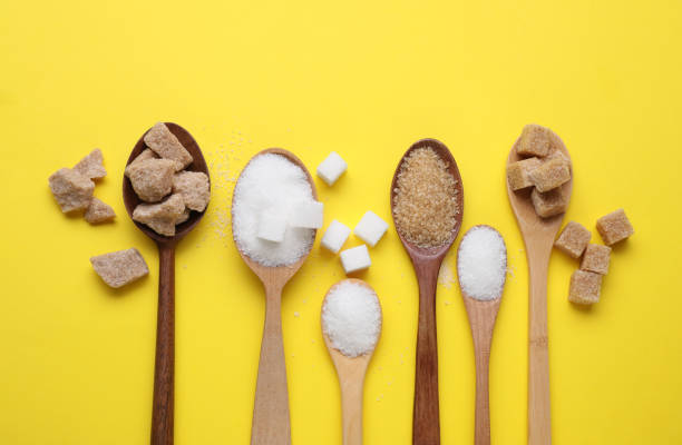 istock Spoons with different types of sugar on yellow background, flat lay 1659938604