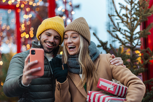 Happy young couple taking a selfie while having fun during a Christmas season