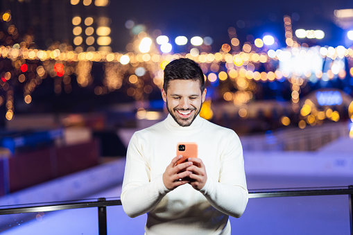 Young man on a New Year's Eve using smart phone and smiling