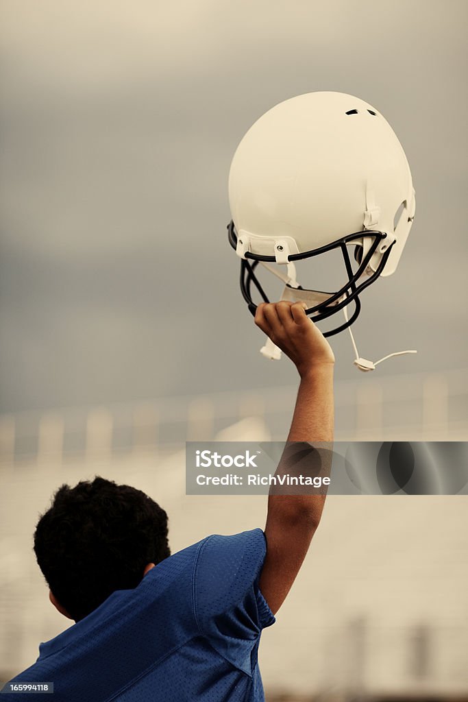 Victory! A youth football player raises helmet after securing the victory. Achievement Stock Photo