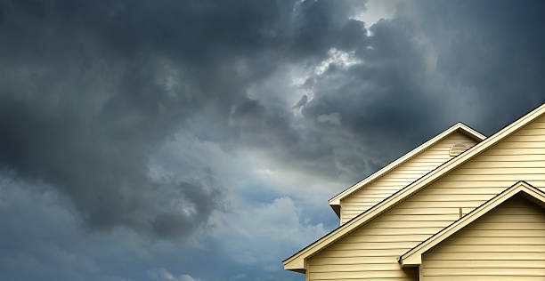 home in stormy day close up shot of yellow siding house over storm clouds. ominous photos stock pictures, royalty-free photos & images