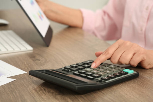 istock Accountant using calculator at wooden desk in office, closeup 1659955296