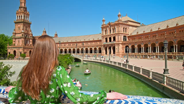 A beautiful tourist girl in a green dress walking in Plaza de España in Seville.