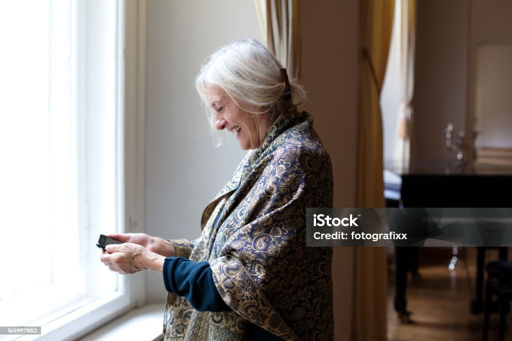 first steps: senior woman has fun with her smartphone elderly lady has fun with her smartphone 60-64 Years Stock Photo