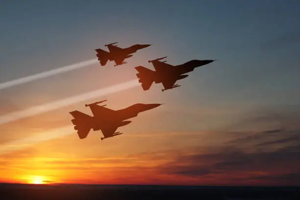 Air Force Day. Aircraft silhouettes on background of sunset. Combat flight of interceptors on a mission.