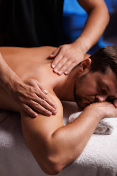istock Handsome man having restorative shoulder massage in spa, enjoying relaxing atmosphere, rebooting after work. Masseuse performs therapeutic massage of the injured hand of visitor, restoring health. 1660019221