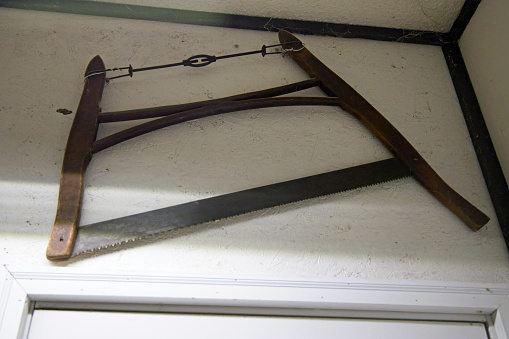 antique wooden bow saw hanging high on a wall over a doorway