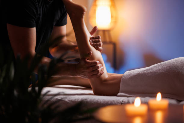 masajista hace un masaje relajante de pies anticelulítico en un spa para una niña en un ambiente cómodo con luz de noche. masaje terapéutico de pies, recuperación después de lesiones, mantenimiento de la salud. - massage therapist massaging sport spa treatment fotografías e imágenes de stock