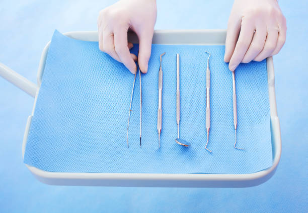 Close up of a tray with dental insturments and the dentist's hands picking up dental tweezers.