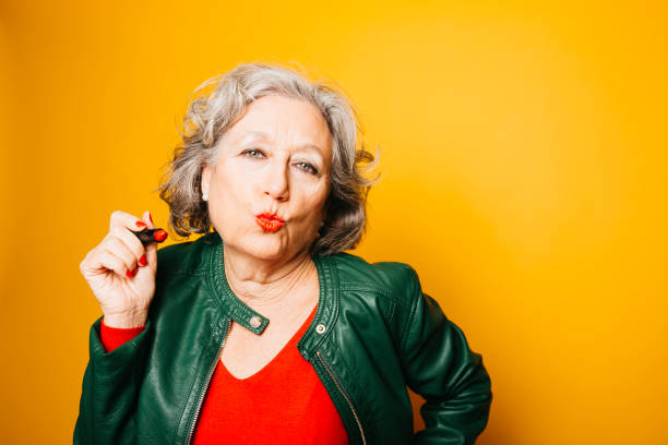 istock Senior woman applying red lipstick. 1660117185