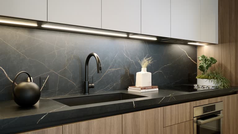 Gorgeous kitchen with white and brown cabinetry, led lightning under cupboards and build-in oven from stainless steel. Black marble matte counter with sink and electric stove