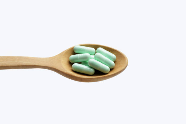 istock Medicine capsules in wooden spoon on white background. 1660153766
