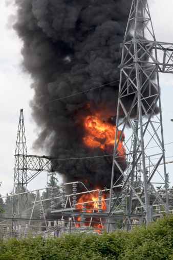 Large fire and dark smoke as an electrical power distribution substation burns out of control.