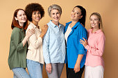 Smiling multiracial women wearing stylish shirts looking at camera isolated on background