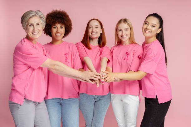 Smiling multiracial women with pink ribbon holding hands together. Breast cancer awareness Group of smiling multiracial women with pink ribbon holding hands together. Breast cancer awareness 21 24 months stock pictures, royalty-free photos & images