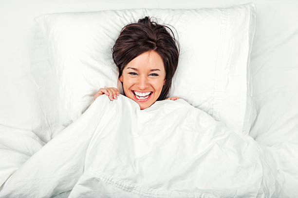 mujer joven feliz en la cama - lying on back fotos fotografías e imágenes de stock