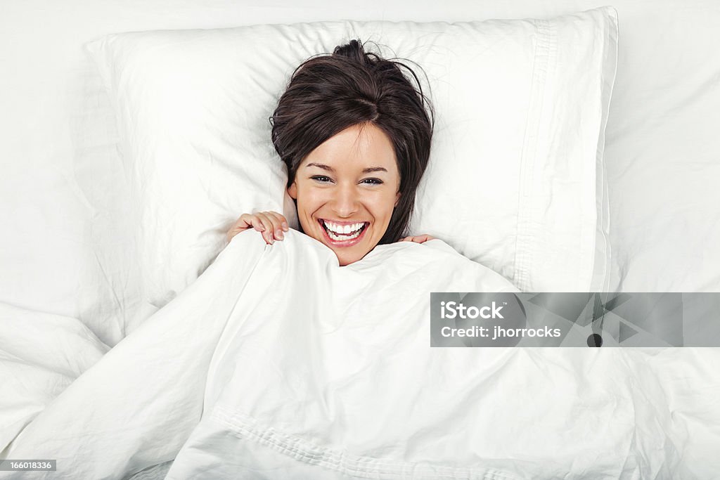 Felice giovane donna a letto - Foto stock royalty-free di Cuscino - Biancheria da letto