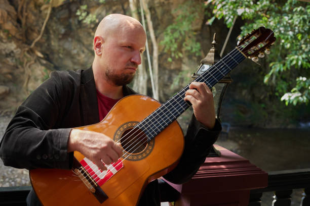 istock Man holding acoustic guitar and practicing in natural surroundings 1660209996
