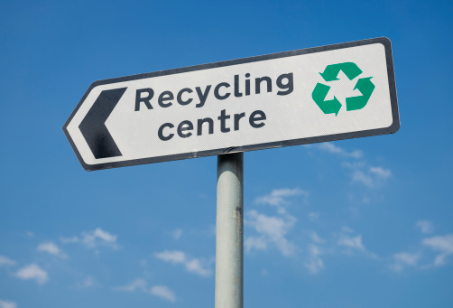 A sign for a public recycling centre, with a green recycling symbol.
