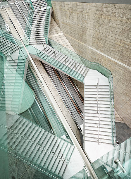 Reflected Modern Architecture - Winding Stairs over Straight Escalators A tall flight of outdoor stairs in Liverpool, England, rising diagonally over a long escalator, and reflected in glass. complexity architecture stock pictures, royalty-free photos & images