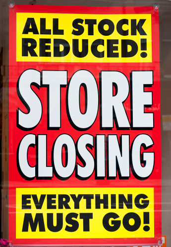 A sign in the window display of a closing shop, advertising clearance prices.