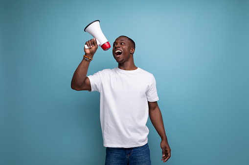 enthusiast 30 year old american male adult in white t-shirt speaks loudly using megaphone.