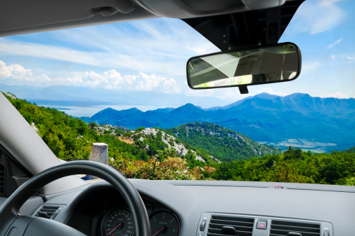 Car interior with dashboard and glass. Beautiful landscape view on mountains, sky, trees and sea. Montenegro, Europe. Clipping path included for window view.