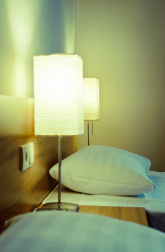 Close-up of elegant comfortable Hotel's beds, pillows, night table and bedside lamps. Processing for retro look, slight vignette added.