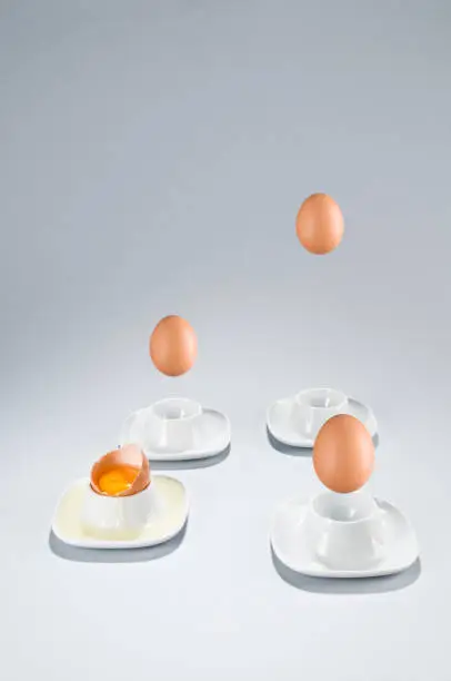Eggs falls into the eggcups, one egg is broken. Raw, yolk egg, copy space, vertical.