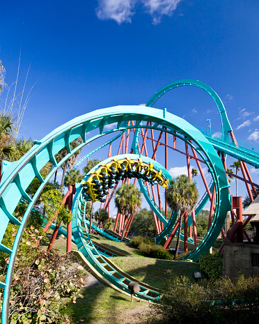 A multi-ethnic group of eight teenagers having fun riding a rollercoaster at an amusement park, smiling and laughing with their arms raised.