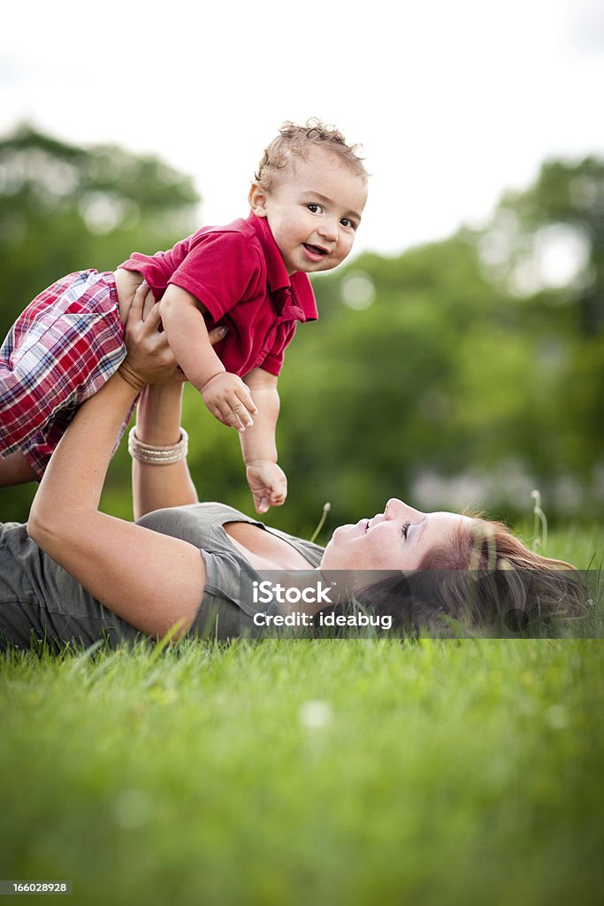 Felice madre con figlio mentre è disteso in erba all'esterno - Foto stock royalty-free di 12-17 mesi