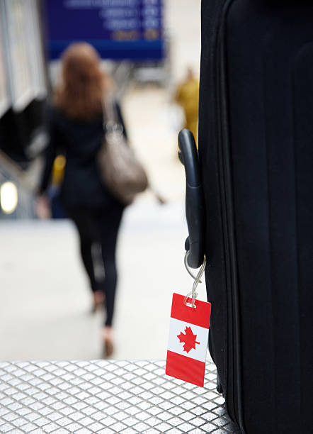 Canada tourism Canada tourism shown by a canadian flag luggage label on suitcase and female traveller as a blur in the background airports canada stock pictures, royalty-free photos & images
