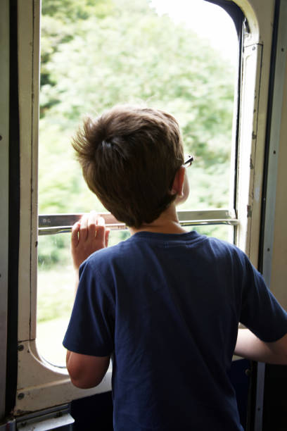 istock Seven year old boy looking out of train window 166032095