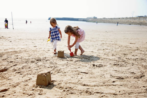 istock Two young girls making sandcastles on the beach 166033198