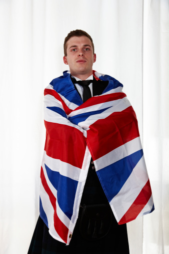 Proud scotsman wearing kilt wrapped in Union Jack