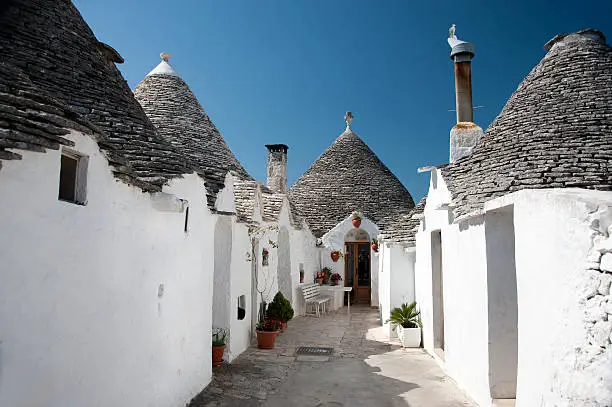 Italy, Apulia.  A trullo (plural = trulli) is a typical  and traditional stone dwelling or storehouse in Apulia, Italy. The little town of Alberobello is very famous for its Trulli. A pinnacle on top of the roof is typical for the Alberobello Trulli.