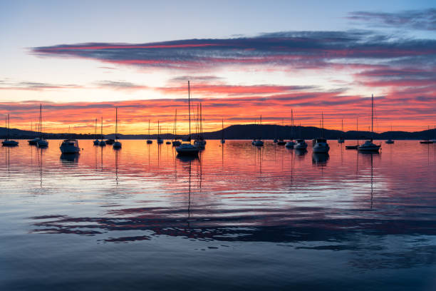 istock Sunrise over the water with boats, reflections and high cloud 1660351394
