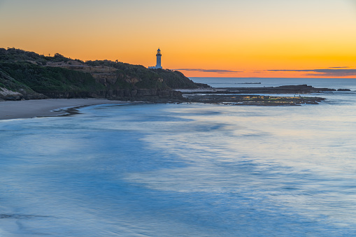 Sunrise seascape with low cloud bank and Norah Head Lighthouse from Soldiers Beach on the Central Coast, NSW, Australia.